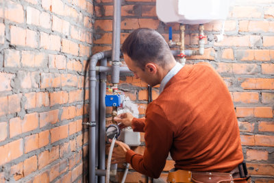 man fixing the pipes of the boiler