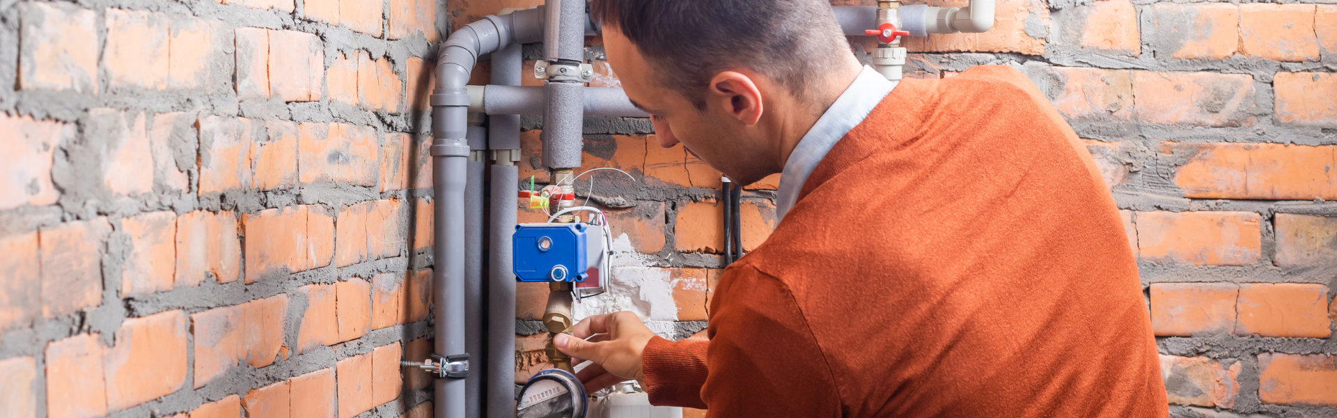 man fixing the pipes of the boiler